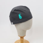 Side view of dark gray scrub cap with turquoise happy gallbladder design on mannequin head