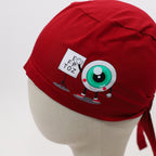 Close-up side view of red scrub cap featuring cartoon eyeball character with eye chart design