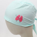 Mint green scrub cap side view showing cute pink lung characters with smiling faces and stick arms