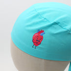 Close-up detail of turquoise scrub cap featuring cute cartoon heart character vinyl transfer