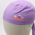 Close-up detail of purple scrub cap featuring dental implant design with teeth and orange gum graphics