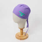 Purple scrub cap with green operating table design shown on mannequin head side view
