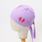 Purple scrub cap with red kidney bean characters shown on white mannequin head, side view