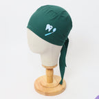 Teal green scrub cap with white tooth and dental mirror design shown on mannequin head side view