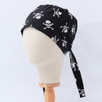 A black scrub cap with a white pirate skull pattern, displayed on a mannequin head.