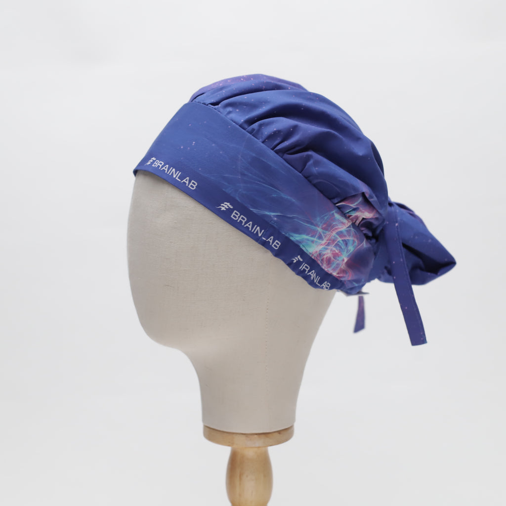 Blue bouffant scrub cap by Medicus Scrub Caps with "Brainlab" branding and neural-inspired design. Reusable, adjustable, and available in 22 colours.