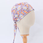 Purple scrub cap with orange pumpkins and autumn leaves pattern shown on mannequin head side view