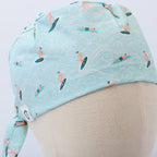 Side view of turquoise scrub cap with surfer and wave pattern showing tie detail