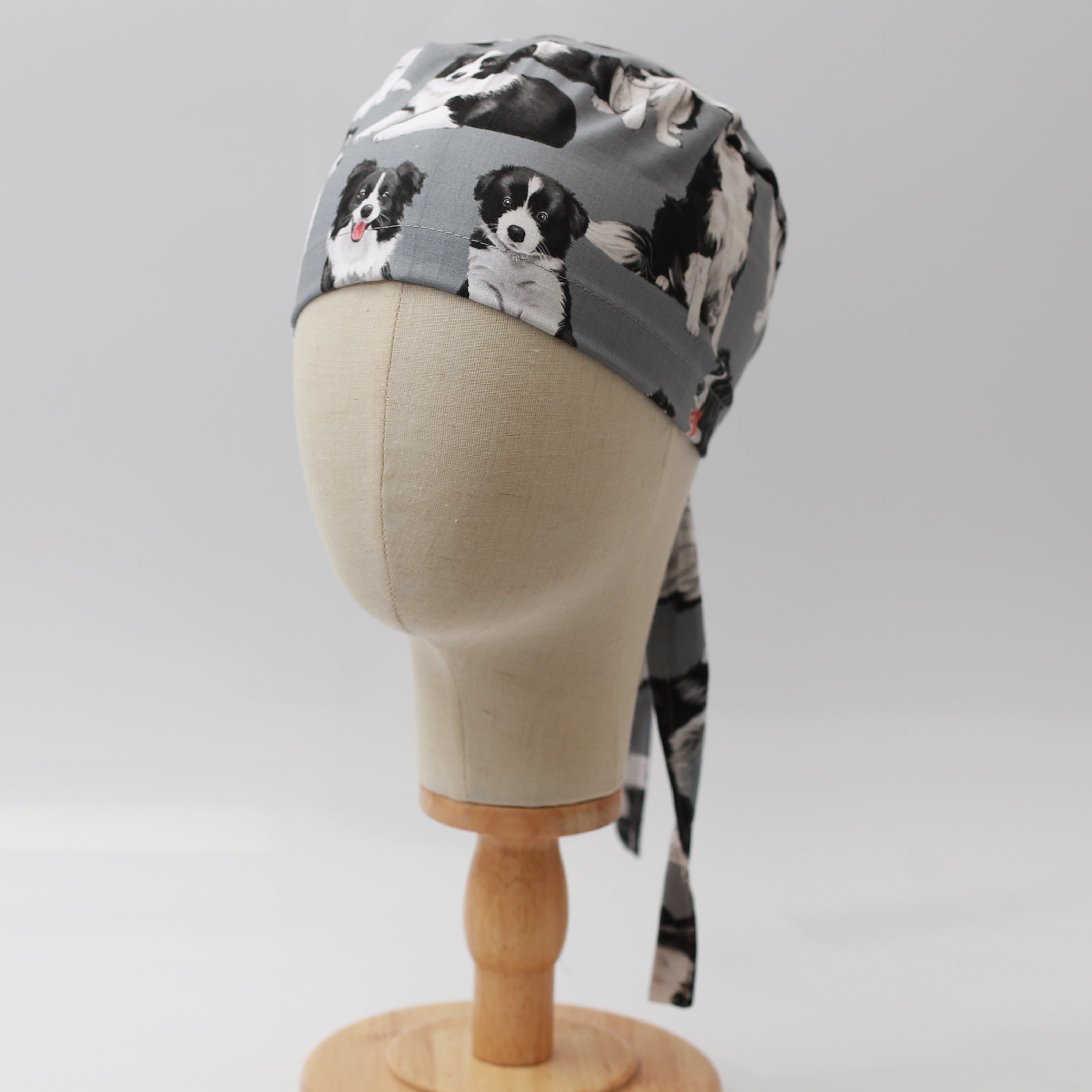 Grey Medicus Scrub Cap featuring a playful Border Collie pattern, displayed on a mannequin head with tie-back detail.