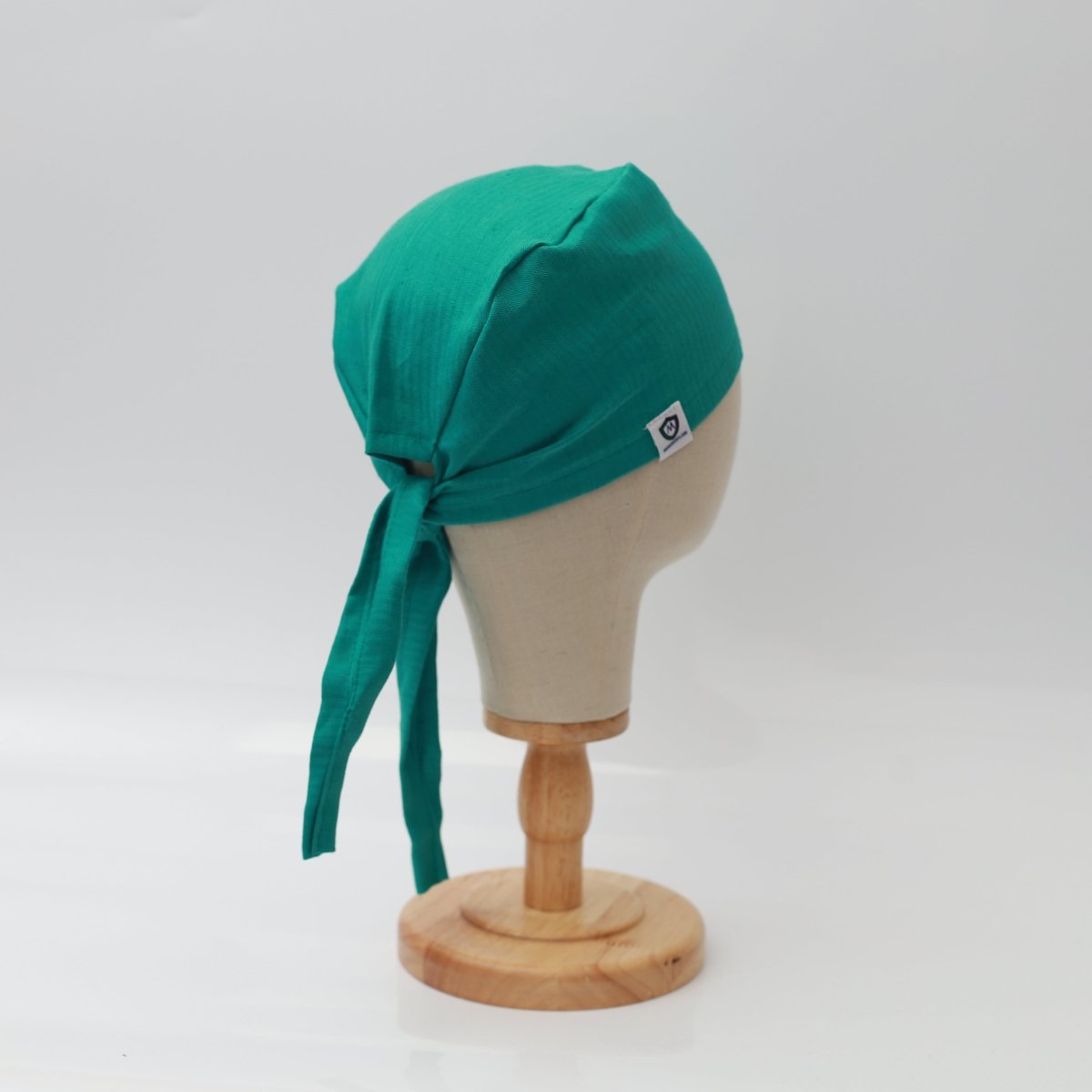 A mannequin head displays a Medicus Scrub Caps 100% Hemp Fabric Reusable Scrub Cap in teal green, featuring back ties. Eco-friendly and stylish.