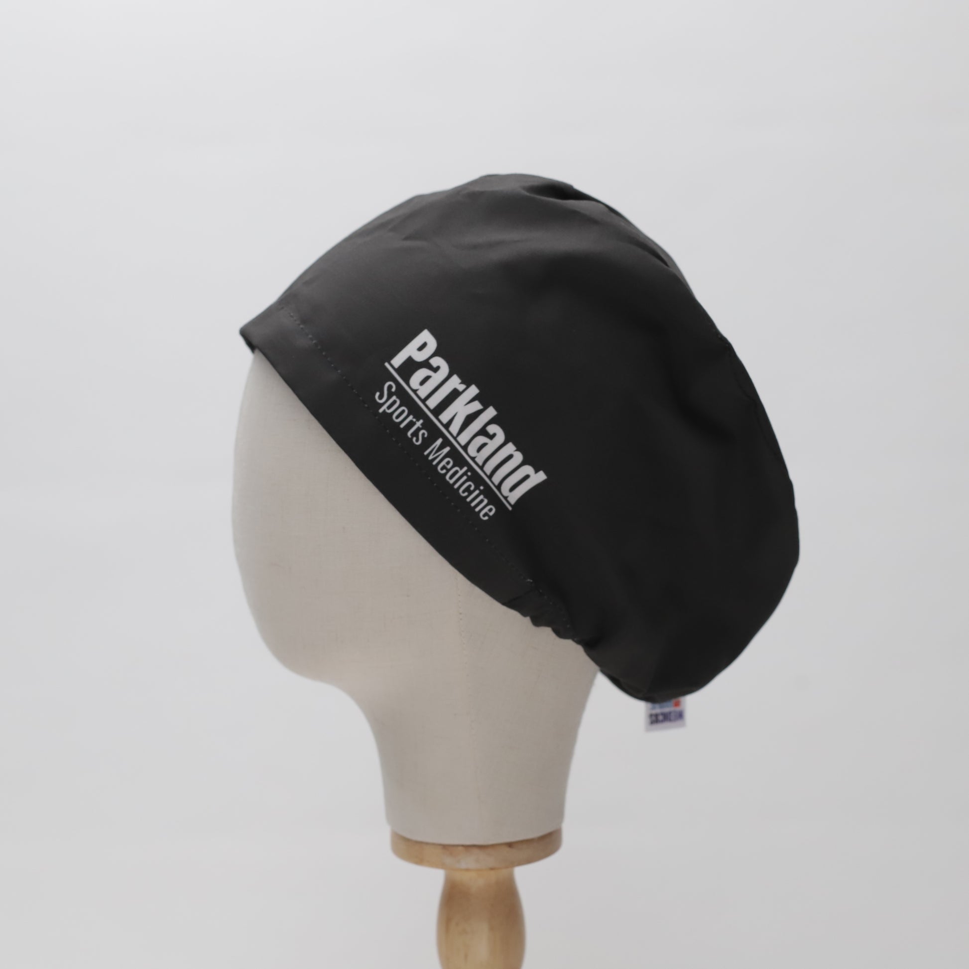 A black Parkland Sports Medicine embroidered scrub cap by Medicus Scrub Caps, displayed on a mannequin head, showcasing a custom-printed design and superior fit.