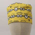 Yellow Minions Eyes scrub cap displayed on mannequin head showing front view with goggle pattern