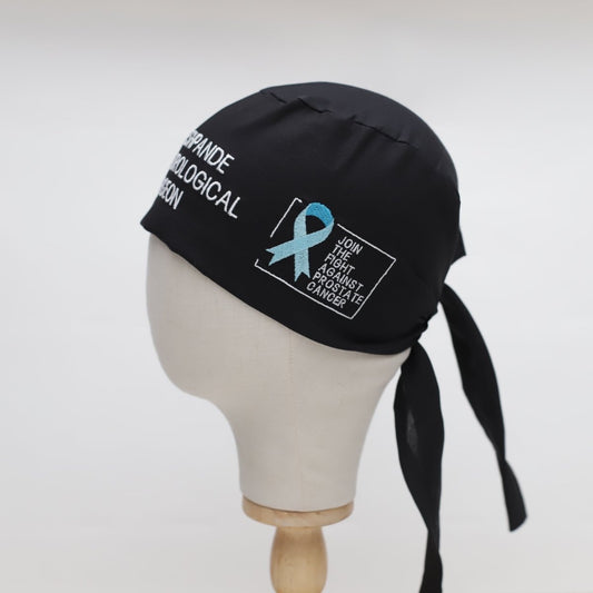 Black Medicus Scrub Cap with embroidered text and a blue ribbon promoting the fight against prostate cancer. Custom design for medical professionals.