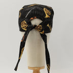 Black scrub cap with golden musical instruments pattern showing back view with tie detail