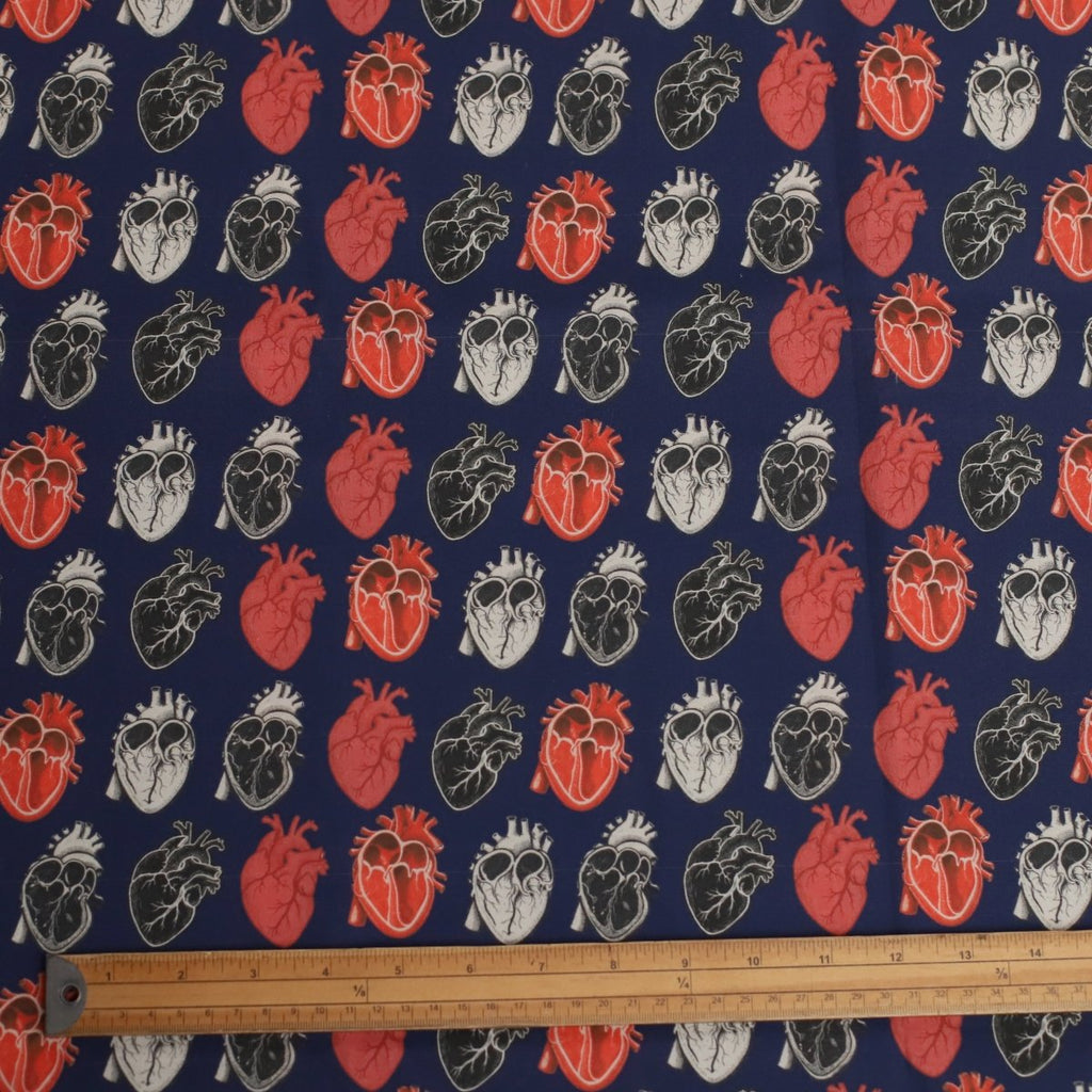 Fabric with anatomical heart pattern on a blue background, measured by a ruler.