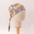 Side profile view of Royal Corgi Dogs scrub cap with orange and white corgis on grey fabric
