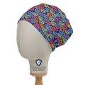 The Love Drug Candy Scrub Cap by Medicus Scrub Caps features colorful, playful skull motifs and medication names, displayed on a mannequin against a white background.