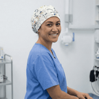 Healthcare worker wearing white scrub cap with colorful cartoon character pattern, side profile view