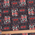 Close-up view of ACDC scrub cap fabric showing black background with red lightning bolts and band logos