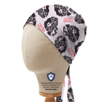 Side view of Kiss Band scrub cap with black skull graphics on light pink fabric