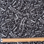 Close-up fabric detail of Music Sheets Swirling Monochrome scrub cap showing white musical notes on black background