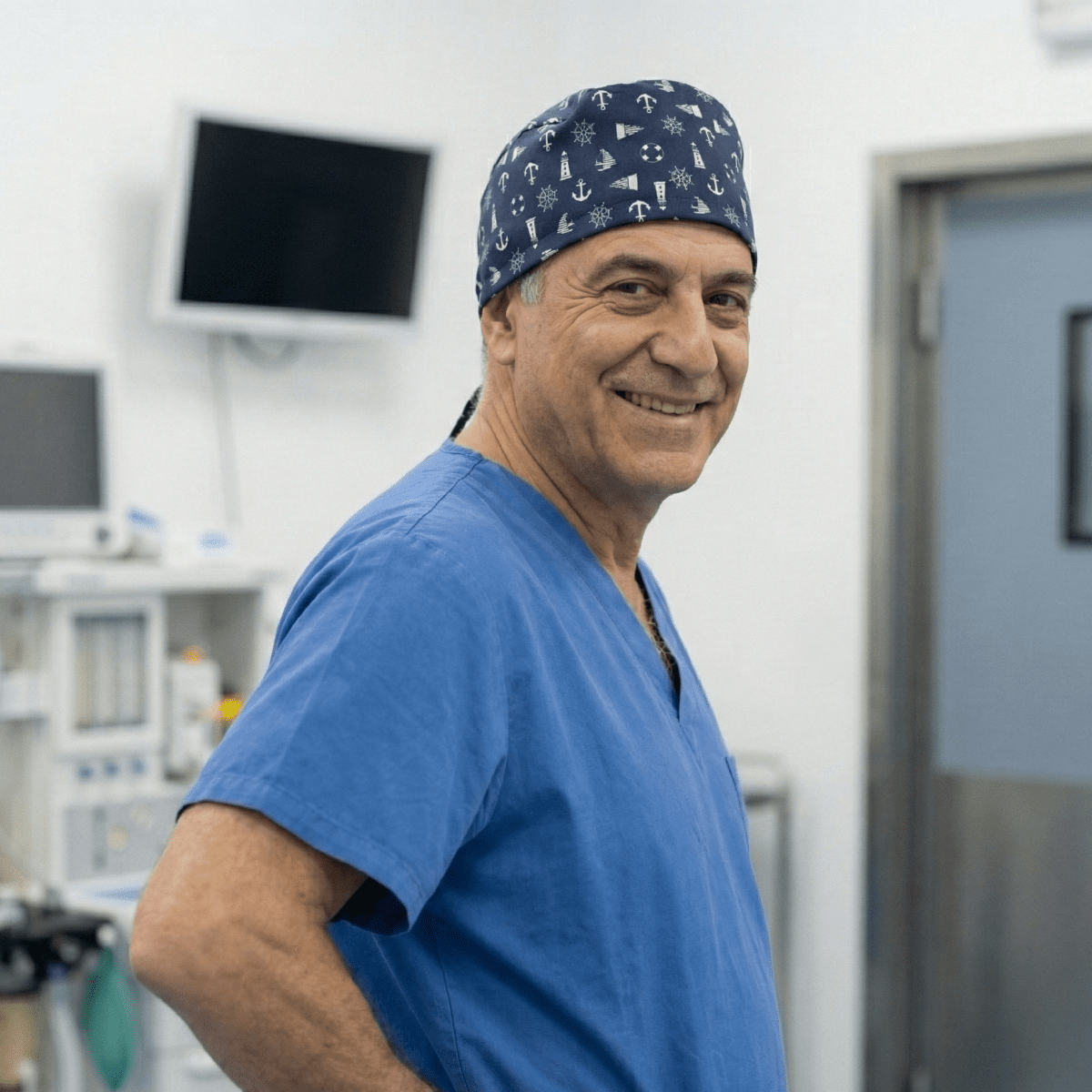 Male healthcare worker wearing nautical ships lighthouses navy scrub cap, smiling in medical facility
