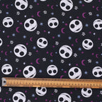 Close-up fabric detail of Nightmare Before Christmas scrub cap showing skull heads with purple stars and moons