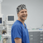 Healthcare professional wearing Nightmare Before Christmas graveyard pattern scrub cap, smiling in medical setting