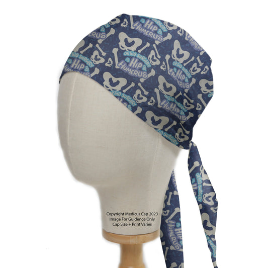 The Orthopaedic Surgery Is Hip + Humerus Scrub Cap by Medicus Scrub Caps features a blue anatomical bone pattern with fun text, perfect for medical professionals.