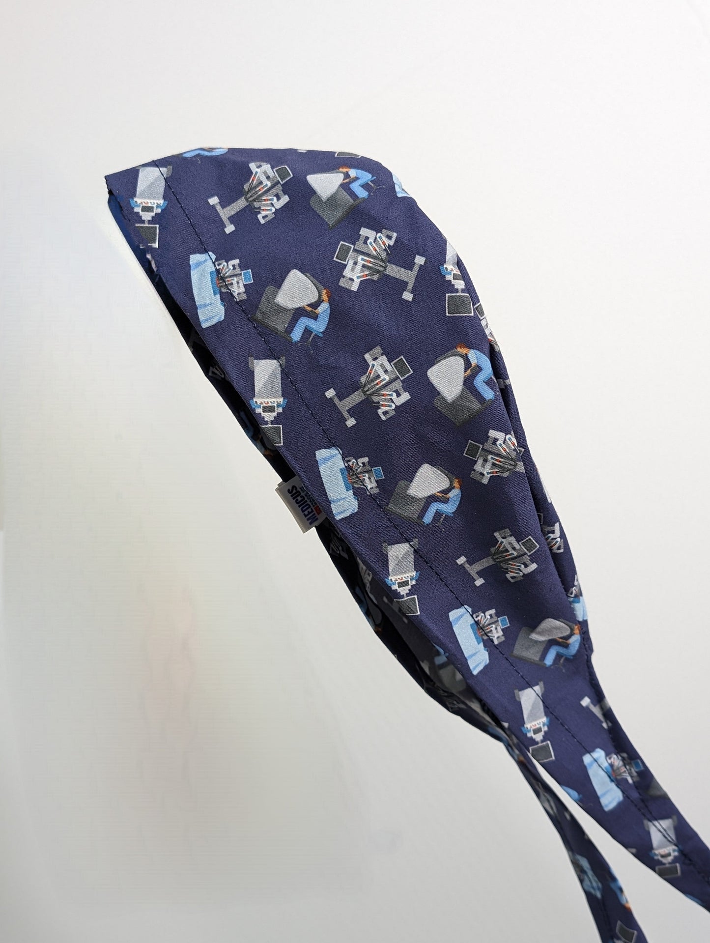 Robotic Surgery Purple Scrub Cap from Medicus Scrub Caps, featuring a surgical robot pattern on dark fabric.