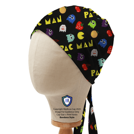 A mannequin head displays the Games Pacman Retro Scrub Cap by Medicus Scrub Caps, featuring a black base with colorful Pac-Man and ghost patterns.