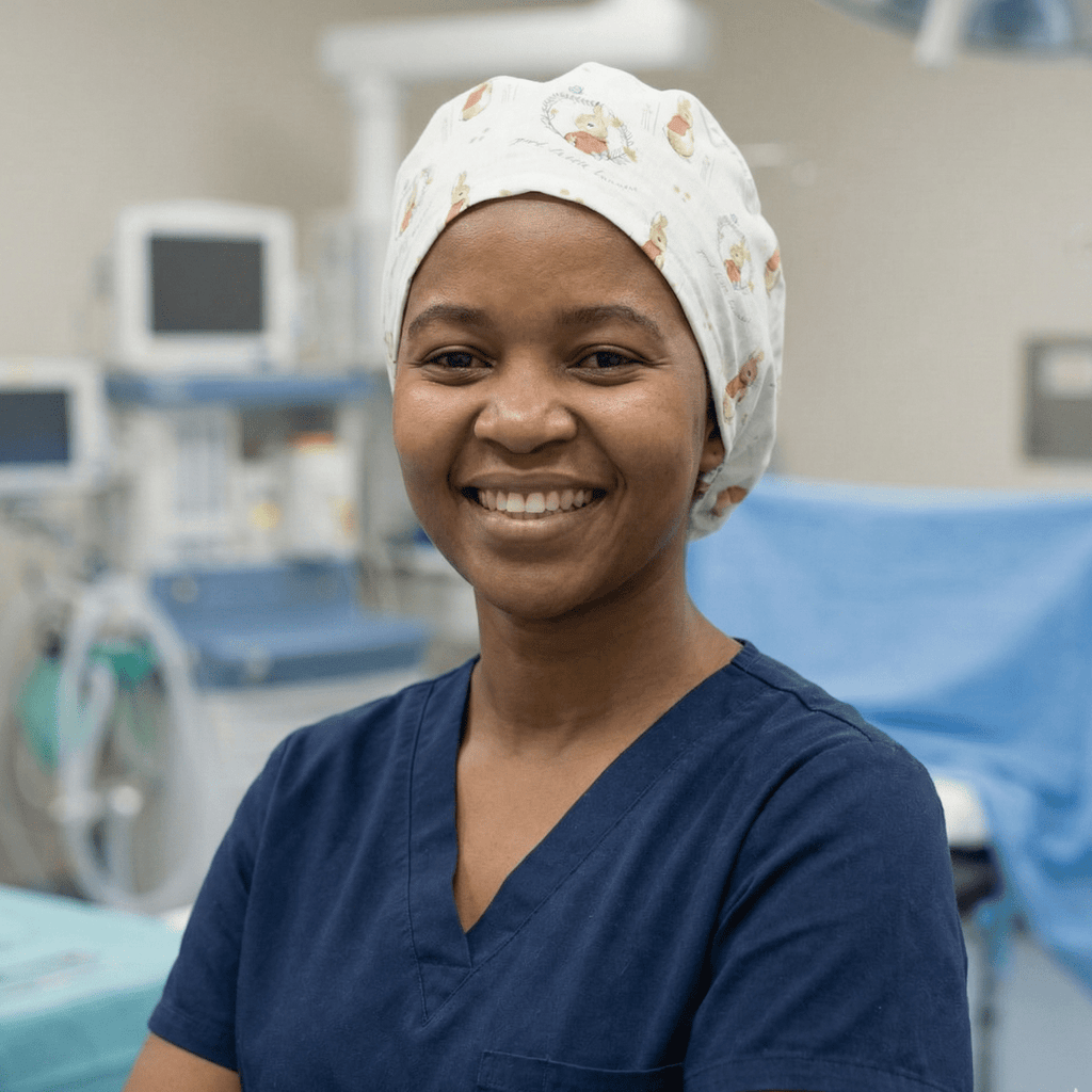 Healthcare worker wearing white Peter Rabbit cartoon scrub cap with grey accents, front view in medical setting