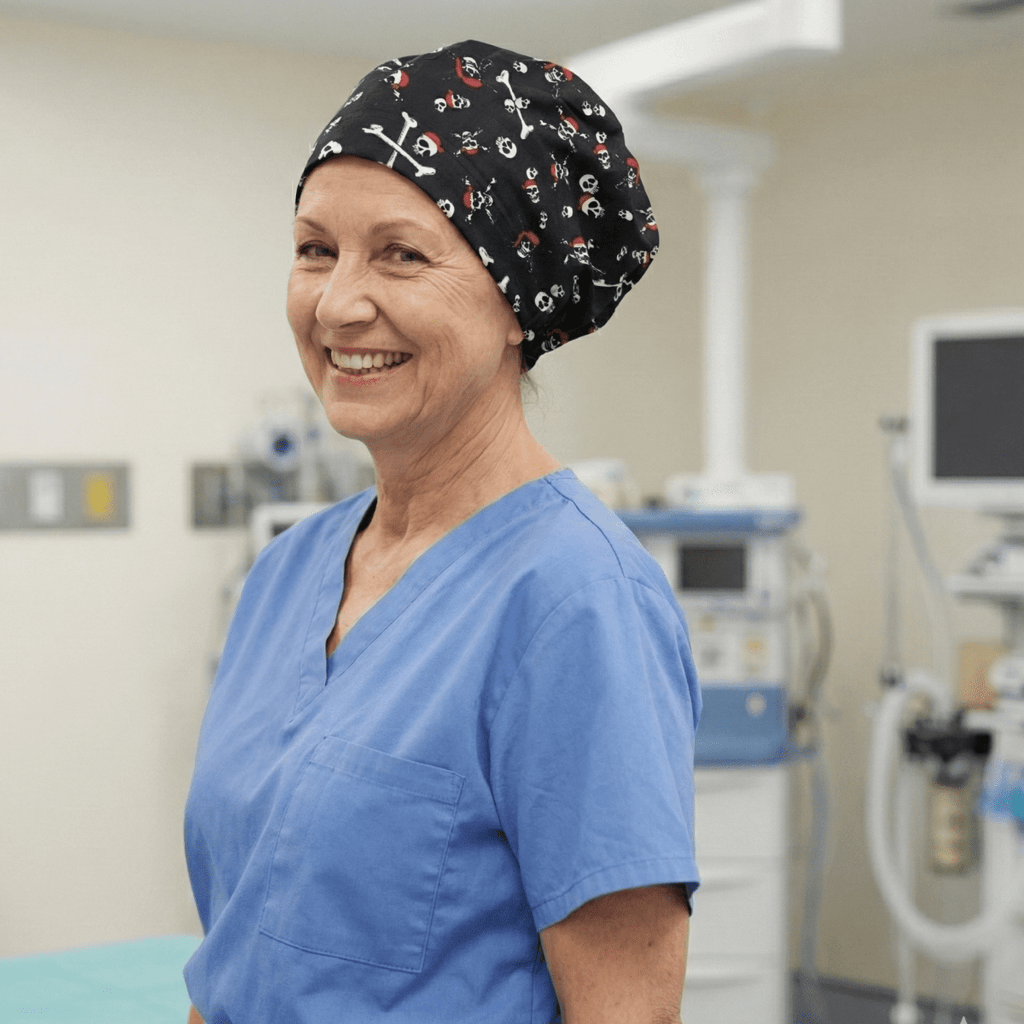 Smiling healthcare worker wearing black pirate skulls and bones scrub cap, side profile view