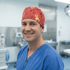 Smiling healthcare worker wearing red Pokemon scrub cap with Pikachu and characters in hospital setting