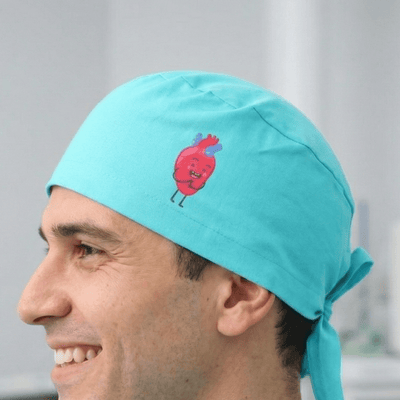 Turquoise scrub cap with cute red heart character design and tie-back closure
