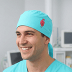 Turquoise scrub cap with red heart design shown in side profile view on smiling healthcare worker