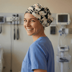 Healthcare worker wearing pug-printed scrub cap with black and beige pattern, side profile view