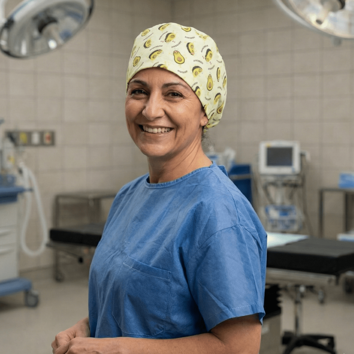 Healthcare worker wearing avocado-patterned scrub cap with yellow and green design, smiling in operating room