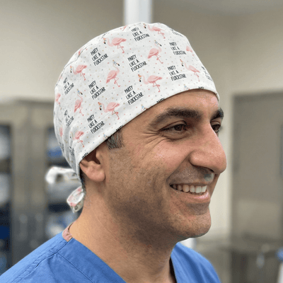 Pink flamingo pattern scrub cap with text print on white background worn by medical professional
