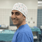 Medical professional wearing white scrub cap with pink flamingo pattern, side profile view in operating room
