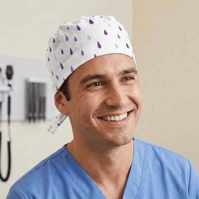 White scrub cap with purple raindrop pattern worn by smiling healthcare professional