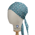A mannequin head displays the Medicus Scrub Caps Robotic Surgery Nerves of Steel green scrub cap, featuring medical-themed illustrations and tie-back design.