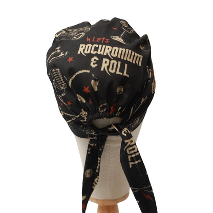 Black Medicus Scrub Cap with "Let's Rocuronium & Roll" text and medical-themed rock and roll pattern, tied at the back.