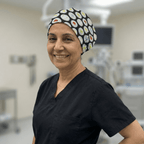 Healthcare professional wearing black petri dish pattern scrub cap, smiling in medical facility setting