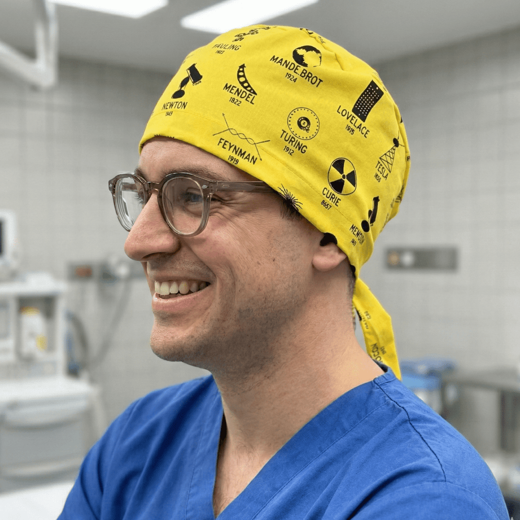 Yellow science symbols pattern scrub cap with tie-back design worn by smiling healthcare worker