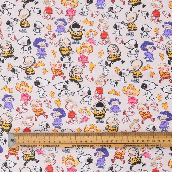 Close-up of fabric featuring Snoopy and Charlie Brown scribble-style cartoon characters with ruler for scale.