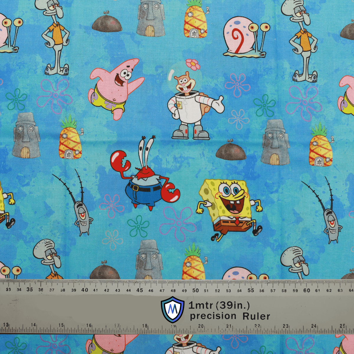 The Spongebob + Friends Scrub Cap by Medicus Scrub Caps features a vibrant blue fabric with beloved characters, pineapples, jellyfish, and tiki heads. Ruler for scale.