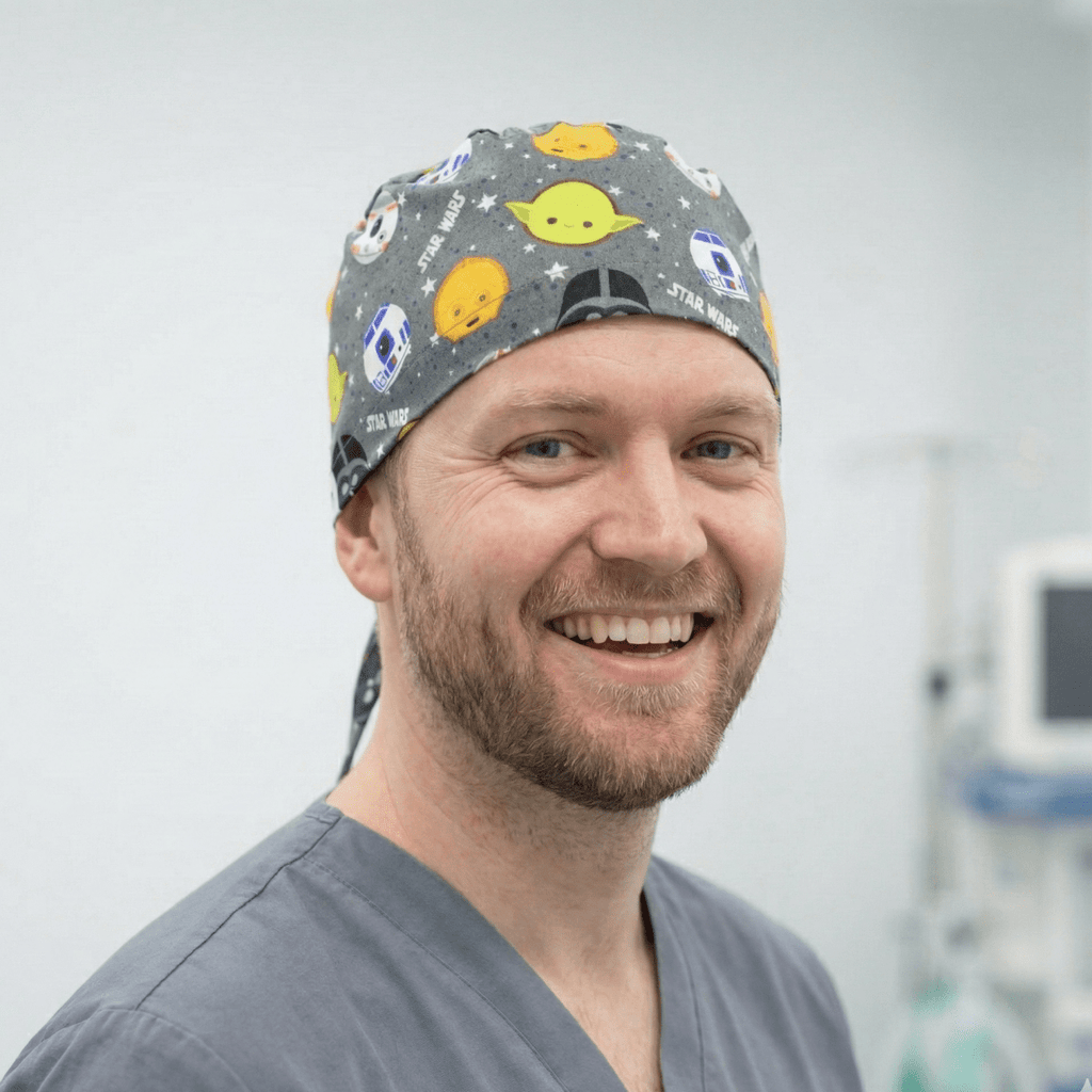 Close-up side view of gray Star Wars Kawaii scrub cap featuring colorful Yoda and character heads pattern