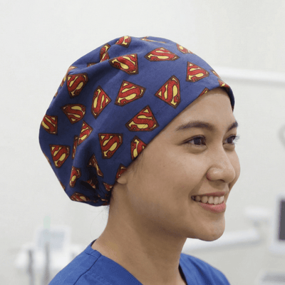 Superman logo pattern on navy blue scrub cap worn by smiling healthcare worker