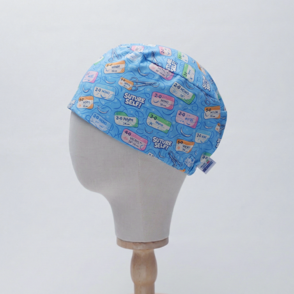 Blue medical humor scrub cap with colorful suture-themed patches displayed on mannequin head